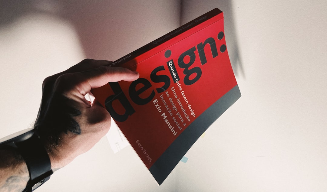 services-02 Tattooed hand holding a red book about design.